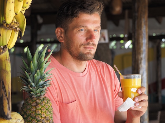 Man holds glass with fresh natural mango juice