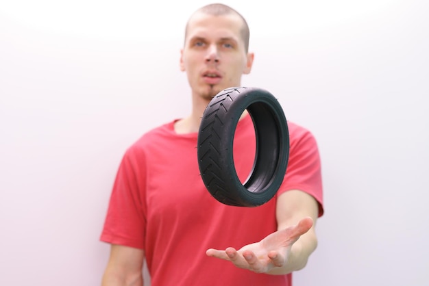 A man holds a hand above a small scooter tire on a white\
background small assistance abs driving evolution front quality\
ride variation repairing biking energy