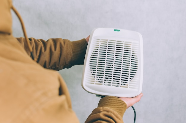 A man holds a heater in his hands on a light.