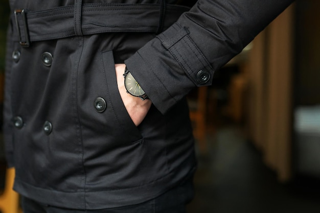 The man holds his hand in his pocket Stylish men's clothing pocket close up Clock on hand on a trench coat background