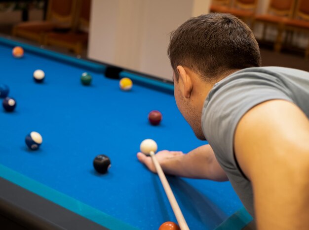 A man holds his hand on a pool table plays snooker or prepares to shoot billiard balls port game snooker billiards billiard balls play billiards