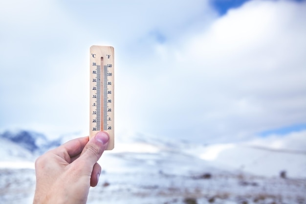 男は手に温度を示す雪の温度計を持っています