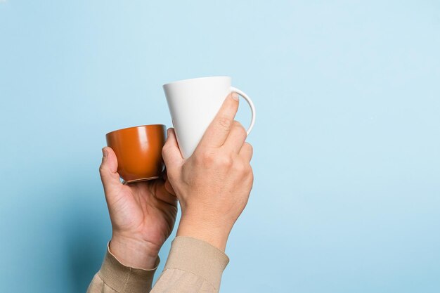 Man holds in his hands various cups of coffee tea drink blue\
background food drink concept copy space place for text