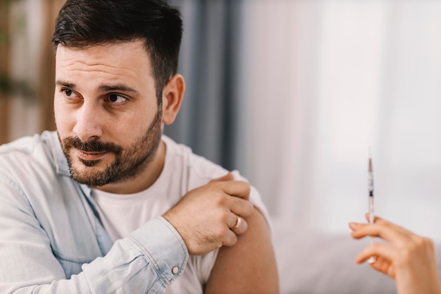 A man holds his sleeve and gets and corona virus vaccine from home