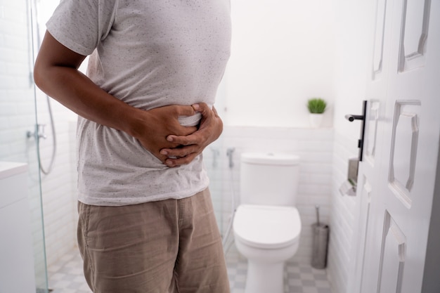 Man holds his stomach painful in the toilet