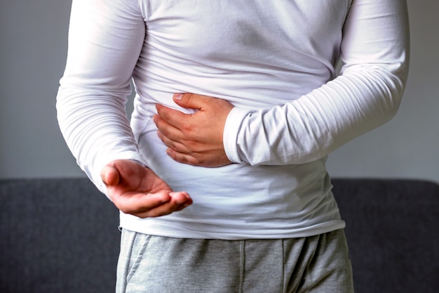 A man holds his stomach, stretches his hand with pills