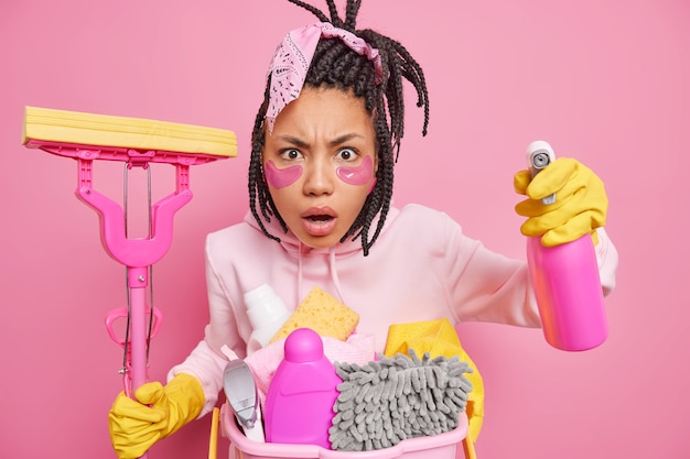 man holds household tools has spring cleaning at home poses on pink 