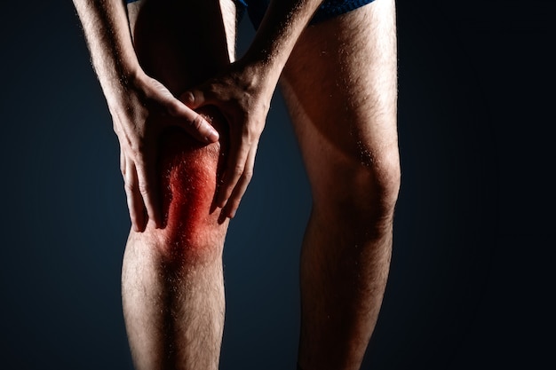 the man holds on to the knee, the pain in the knee