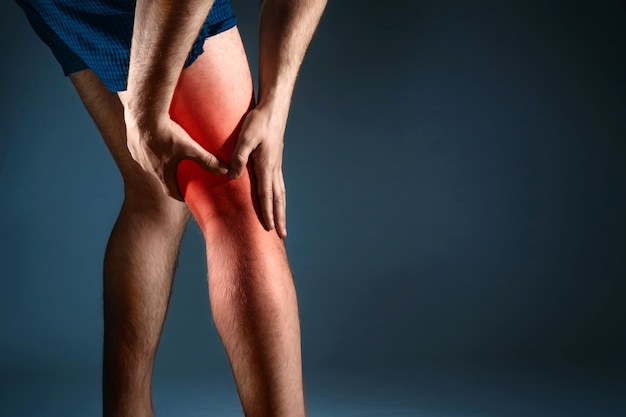 the man holds on to the knee, the pain in the knee