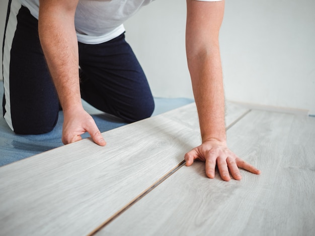 A man holds a laminate board in his hands. The repair process in the room