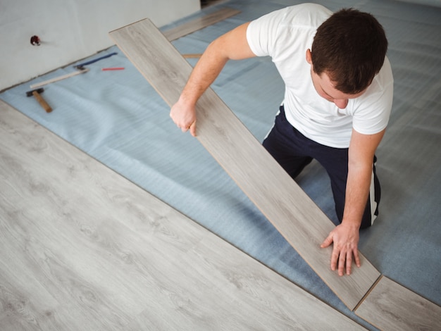 A man holds a laminate board in his hands. The repair process in the room