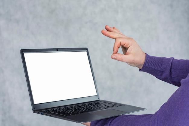 Man holds a laptop in his hands with a mockup of a white screen on a light background