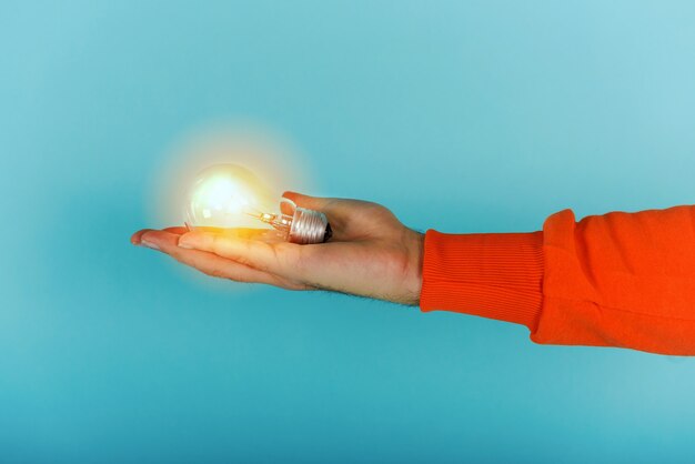 Photo man holds a lightbulb in hand on cyan