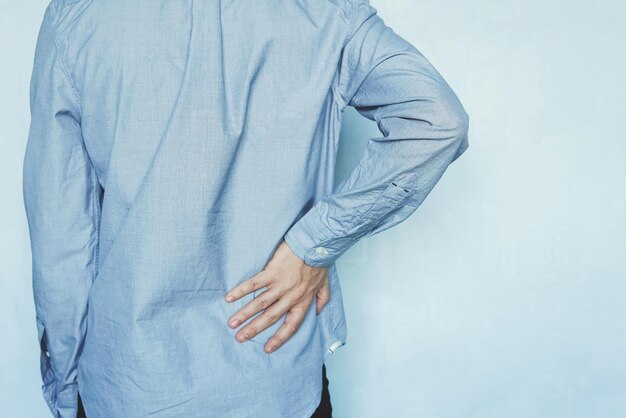 A man holds the liver on a blue background Pain in the abdomen Cirrhosis of the liver Closeup Tired businessman with back pain holding her back kidney stone copy space