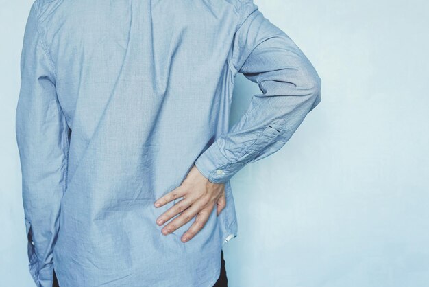 A man holds the liver on a blue background pain in the abdomen cirrhosis of the liver closeup tired businessman with back pain holding her back kidney stone copy space