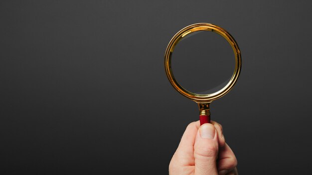 Man holds a magnifier on a black wall