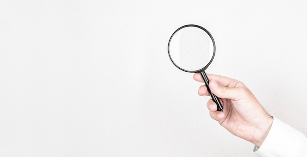 Photo man holds magnifying glass on wall