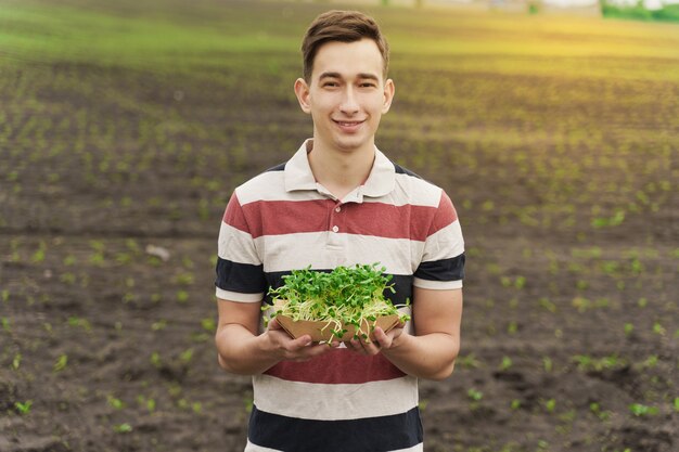 Photo man holds microgreen of sunflower seeds in the field