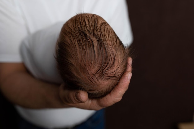 A man holds a newborn baby's head in his hands.