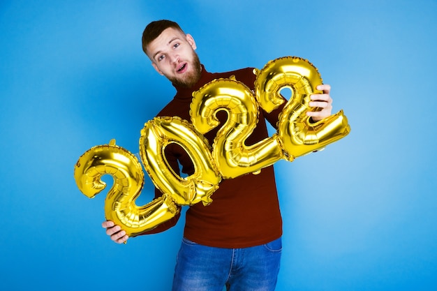 A man holds the numbers 2022 from golden balloons. the coming new year