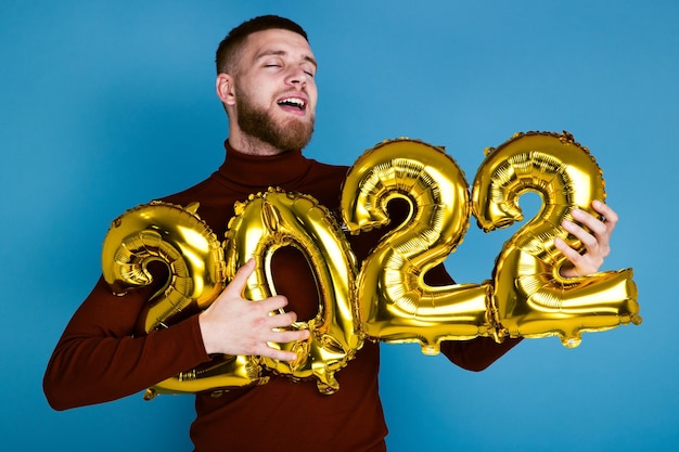 A man holds the numbers 2022 from golden balloons. The coming new year