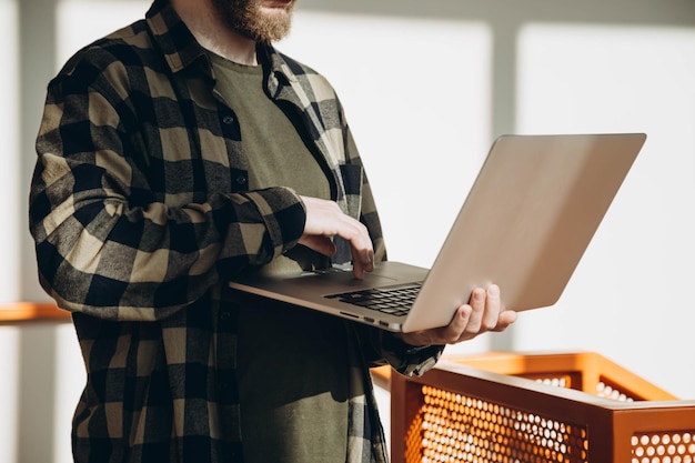 Мужчина держит открытый ноутбук в солнечном офисе интерьера близко