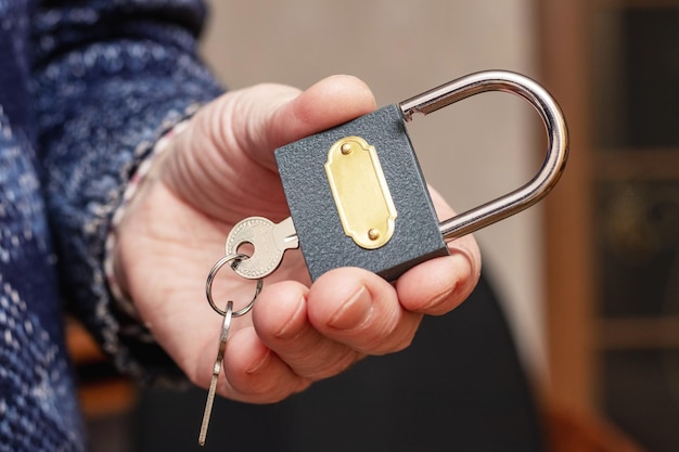 A man holds a padlock with keys in his hand