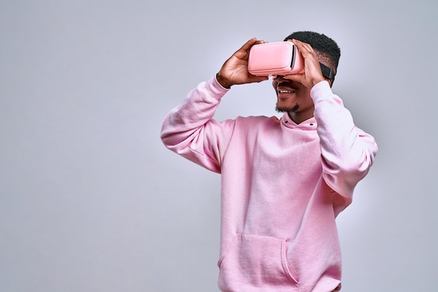 L'uomo tiene occhiali virtuali rosa e gode di ciò che vede il concetto di realtà virtuale con tecnologia divertente