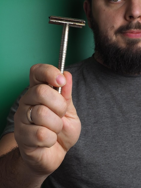 A man holds a razor with a ring on his finger.