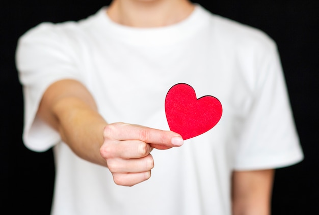 man holds red heart in his hands