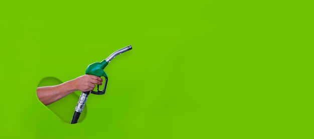 Man holds a refueling gun in his hand for refueling cars isolated on a green background Gas station with diesel and gasoline fuel closeup