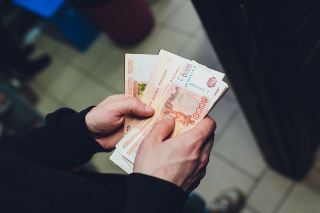 A man holds rubles and dollars in his hand, a businessman holds money in his hand.