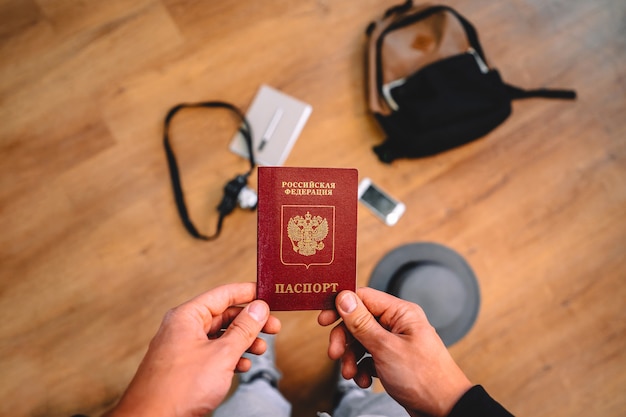 L'uomo tiene un passaporto russo con uno zaino e accessori da viaggio