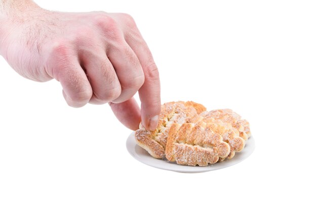 A man holds a sweet biscuit with sugar over a plate