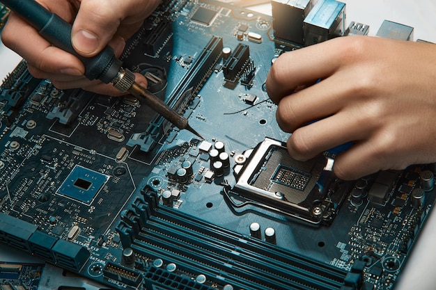 Un uomo tiene uno strumento per riparare l'elettronica, assemblando manualmente un circuito di saldatura.