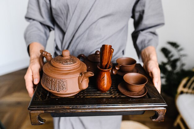 A man holds a tray with a set for a Chinese tea ceremony.