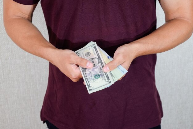 man holds a wad of dollars in his hands US Dollars