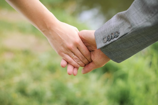 A man holds a woman's hand Hands of the bride and groom with an engagement ring closeup