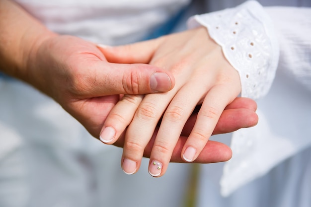 Man holds womans hand in his palm on white