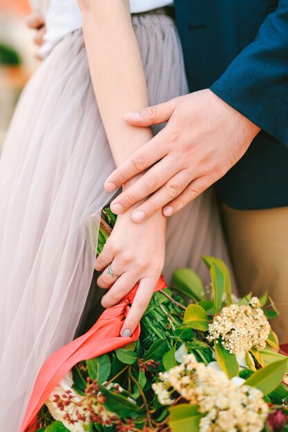 Man holds womans hand with a bouquet of flowers in her hands closeup