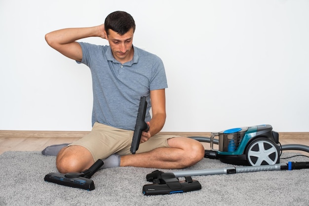 A man at home chooses exactly which brush to attach to the vacuum cleaner