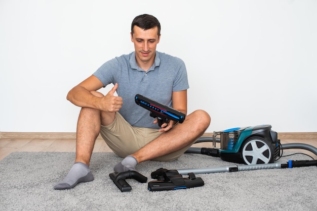 A man at home chooses exactly which brush to attach to the vacuum cleaner