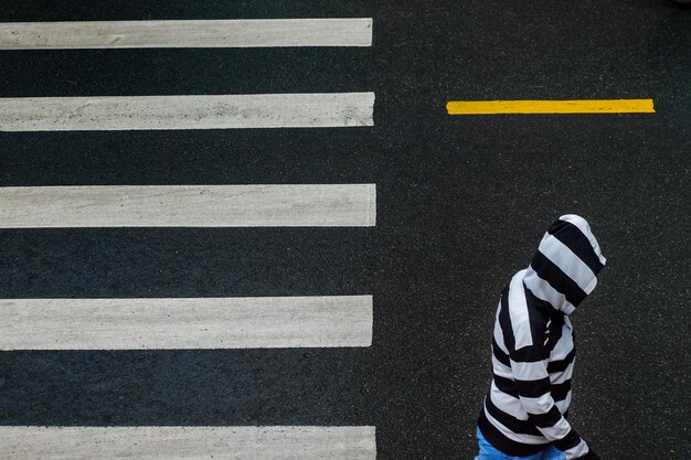 フードをかぶった男が道路を横断している