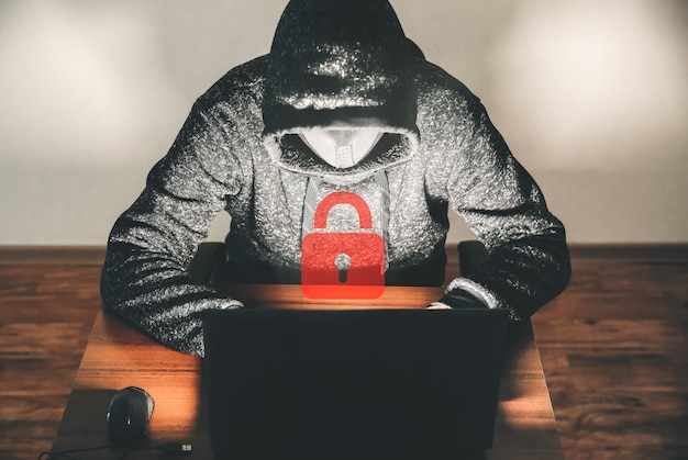 パーカーを着た男が個人データをハッキングしています。情報セキュリティー。情報の概念の保護。不正なパスワード。