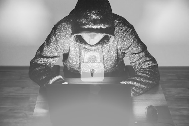 パーカーを着た男が個人データをハッキングしています。情報セキュリティー。情報の概念の保護。不正なパスワード。