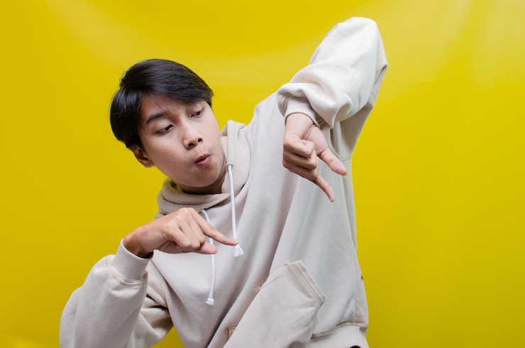 Photo 후드티를 입은 남자가 자신의 손과 손목을 가리킵니다.