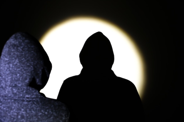 Man in hoodie. Shadow in the spotlight.