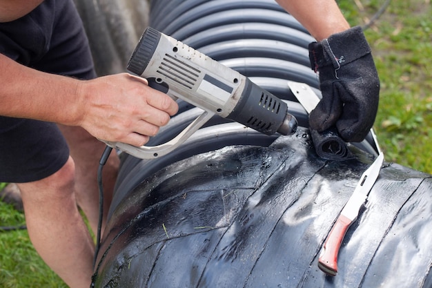 Man hot gun melts plastic around pipe