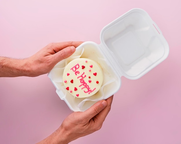 Man houdt Bento-cake vast met tekst Wees blij in afhaaldoos