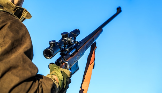 Man houdt een geweer in zijn handen, wapen. Shooter waarneming in het doel.